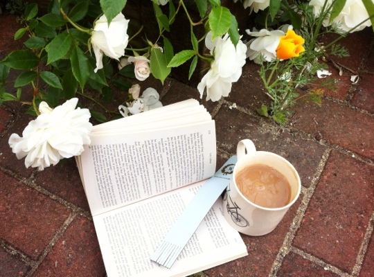 Open book and cup of tea on the paving