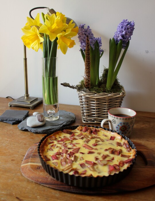 Rhubarb tart on table next to flowers